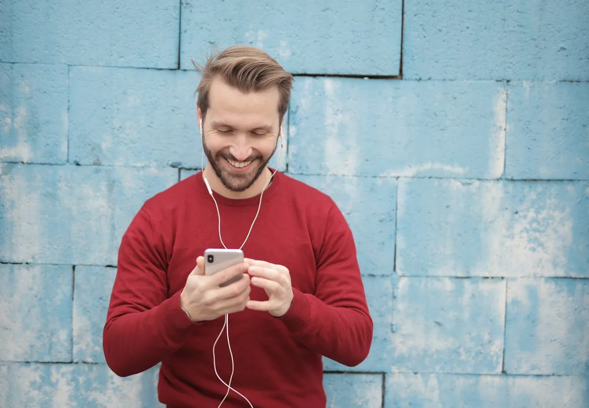 Cheerful young man listening to music on earphones outdoors